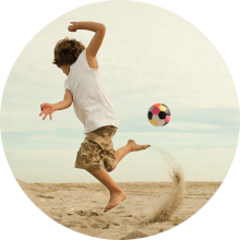 Ein Junge spielt Fußball am Strand