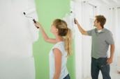 Frau und Mann streichen eine farbige Wand in der Wohnung wieder weiß.