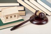 Richterhammer vor Büchern und kleinem Holzhaus