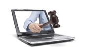 Arm mit Richterhammer in der Hand ragt aus einem Laptop hervor.