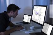 Man sitzt vor drei Laptops und programmiert.