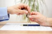 Hände über Vertrag bei Schlüsselübergabe