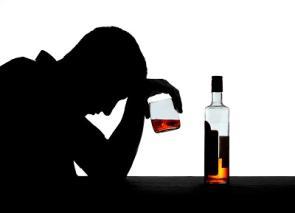 Schattenbild zeigt einen Mann mit gesenkten Kopf beim Alkoholkonsum.