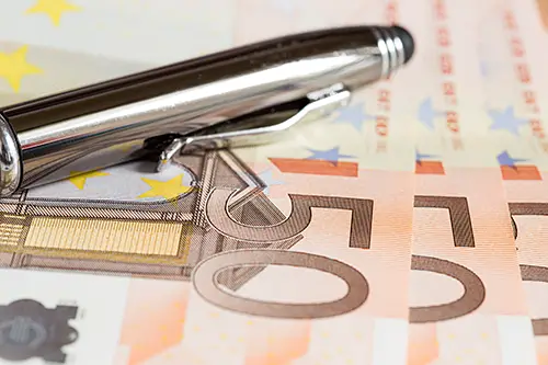 Drei Fünfzigeuroscheine und ein Stift liegen auf einem Tisch.