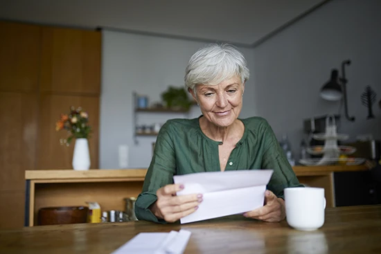 Rentenbescheid + Renteninformation: Ältere Frau liest einen Brief