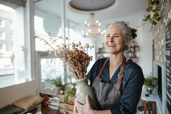 Rentenniveau: Ältere Frau im Blumenladen mit Blumenstrauß