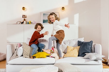 Rentenversicherung für Kinder: Zwei spielende Mädchen auf einem Sofa