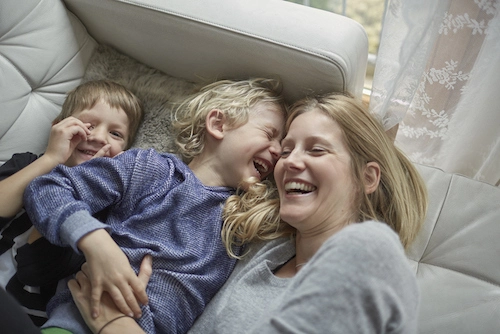 Todesfallversicherung: Mutter mit zwei kleinen Kinder auf einem Sofa.