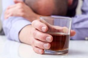Mann vor Glas mit Alkohol