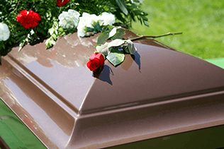 Sarg mit Blumen bei typischer Erdbestattung auf Friedhof