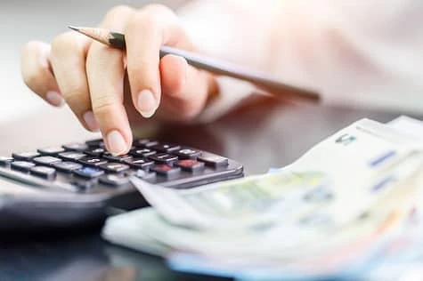 Frauenhand mit Taschenrechner, Bleistift und Euro-Geldscheinen