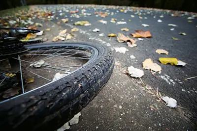 Ein umgestürztes Fahrrad liegt auf einem Radweg voller Laub.