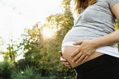 Schwangere Frau hält ihren Bauch - Geburt - Überprüfung Unfallversicherung