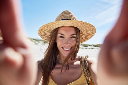 Reiseunfallversicherung: Frau mit Sonnenhut am Strand