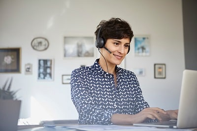 Junge Frau mit Headset und Laptop - Unfallversicherung im Homeoffice