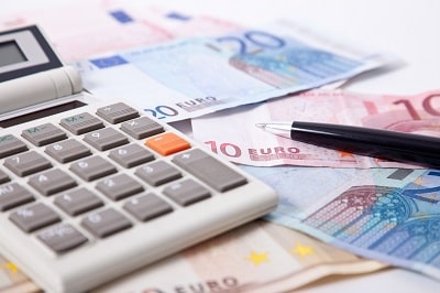 Taschenrechner mit Euroscheinen und Kugelschreiber - Beitrag der Unfallversicherung berechnen
