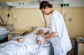 Krankenpflegerin am Krankenhausbett einer älteren Patientin.