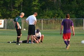 Spieler kümmern sich um verletzten Fußballer.