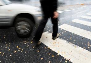 Fußgänger überquert Straße als ein Auto kommt
