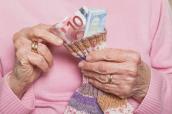 Seniorin entnimmt Geldscheine aus einem Sparstrumpf