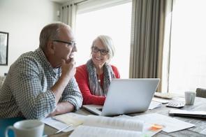 Rentner-Paar macht seine Finanzen am Laptop.