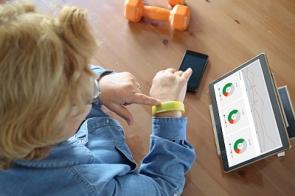Ältere Frau mit Fitness-Tracker, Handy und Tablet