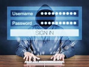 Unkenntlicher Mann im Kapuzenpulli hackt sich in einen Computer.
