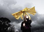 Frau mit kaputtem Schirm im Regen