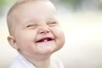 Kind mit ersten Zähnen lacht
