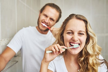 Mann und Frau beim Zähneputzen.