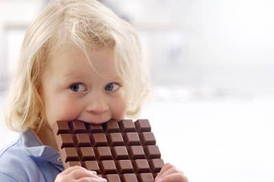 Mädchen beißt in eine Tafel Schokolade