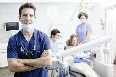 Zahnarzt mit Personal und Patientin in Praxis